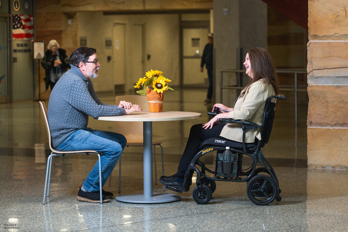 User enjoying conversation while seated comfortably in the Jazzy Carbon 27X lightweight power chair.