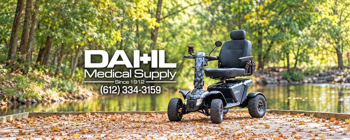 Camouflage Baja Wrangler 2 recreational mobility scooter on a leaf-covered path beside a wooded pond, with the white Dahl Medical Supply logo on the left.