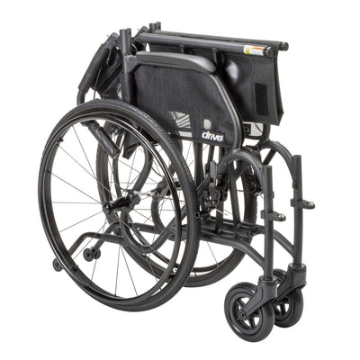 Black AeroFly wheelchair folded for storage and transport, with the backrest lowered and rear wheels attached.