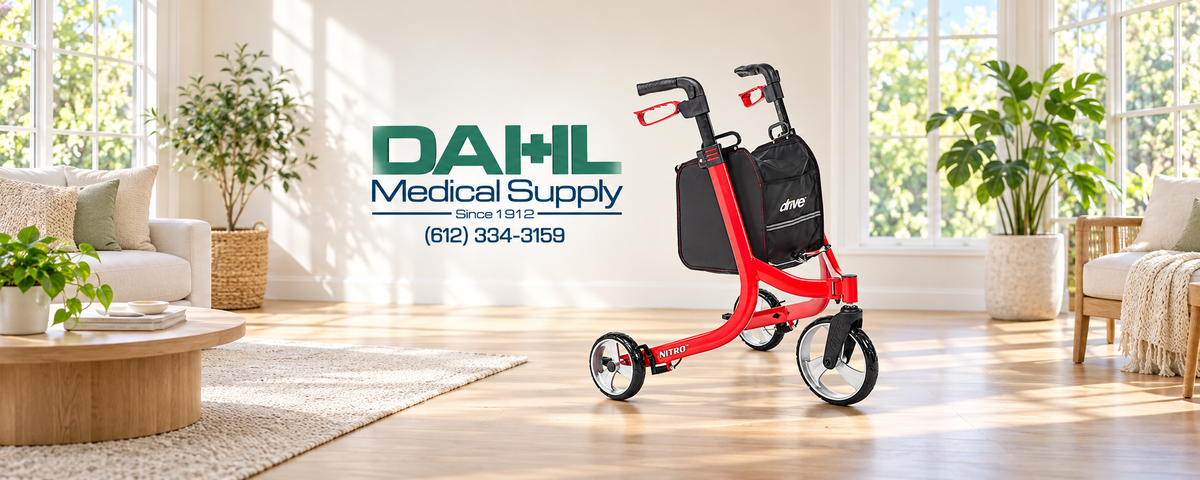 Red Drive Nitro three-wheel rollator with a black storage bag beside the Dahl Medical Supply logo in a bright living room with natural lighting, large windows, and indoor plants.