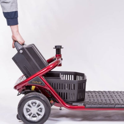 Golden LiteRider scooter battery pack being lifted out by its built-in handle for convenient charging and transport.