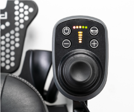 Close-up of the Jazzy EVO powerchair joystick controller showing the power button, horn, speed adjustment buttons, and illuminated battery and speed indicators.