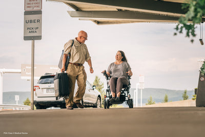User driving the Pride Jazzy Carbon through an airport pickup area.